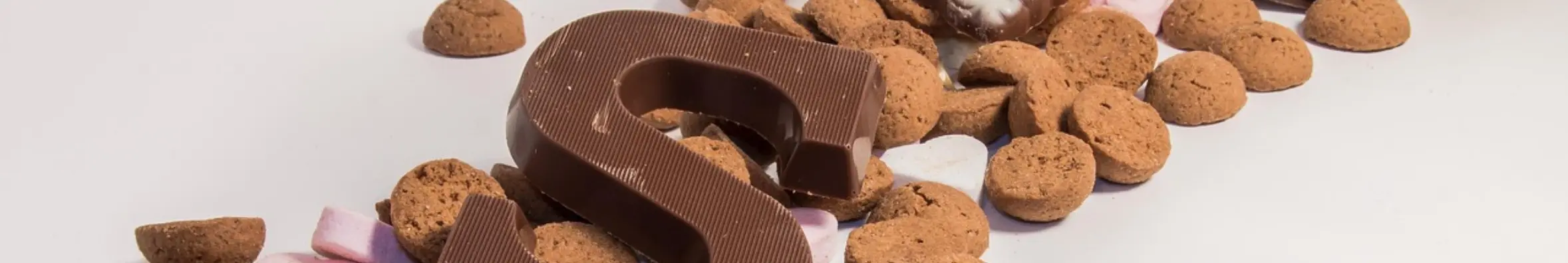 Sinterklaassnoepgoed op witte achtergrond. Chocoladeletter S, kruidnoten en sinterklaas chocolaatjes