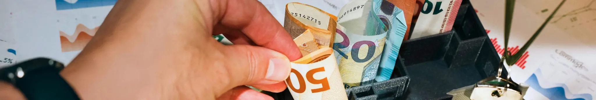 Hand pakt een biljet van 50 euro van een tafel met contant geld.