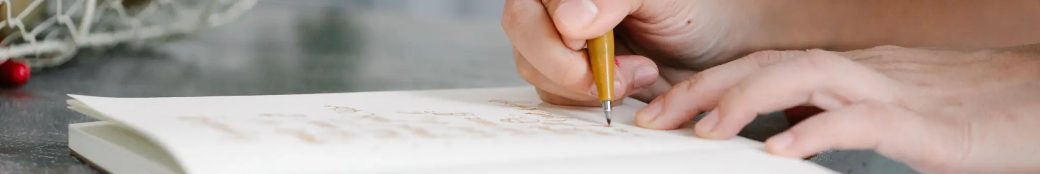Persoon schrijft een boodschappenlijst op papier met een pen.