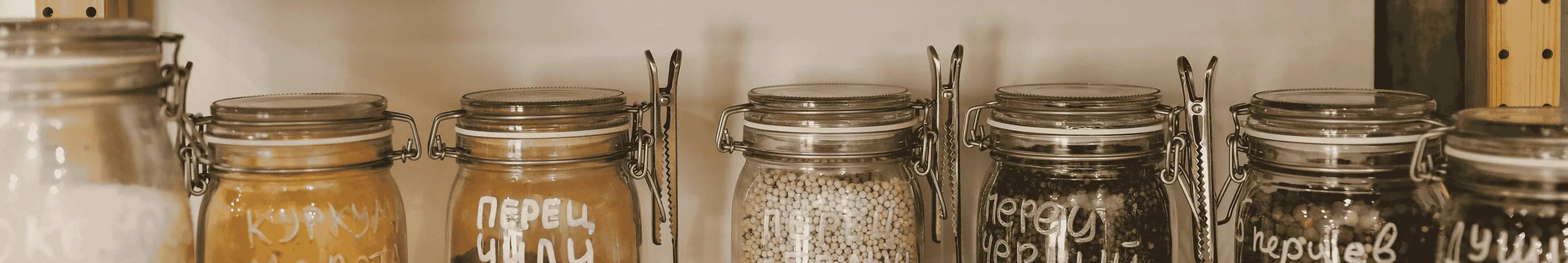 Bocaux remplis de produits longue conservation comme des pâtes et du riz dans une étagère en bois.