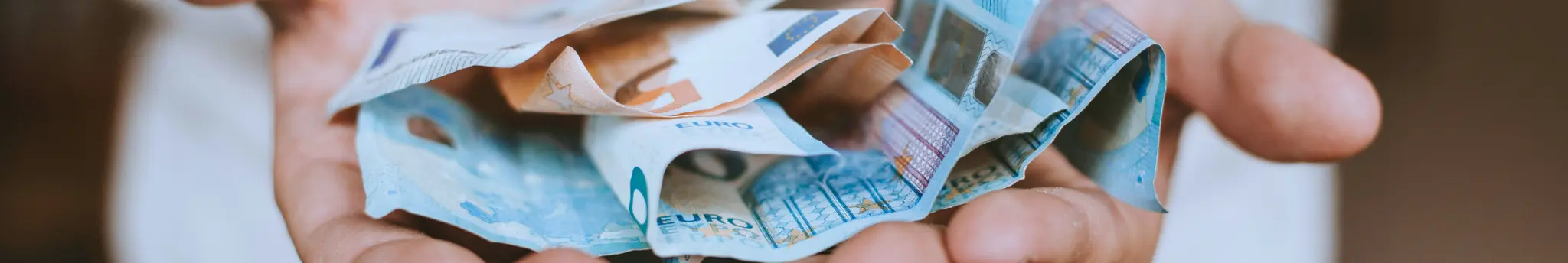 Persoon houdt eurobiljetten vast na te hebben bespaard op dagelijkse uitgaven.